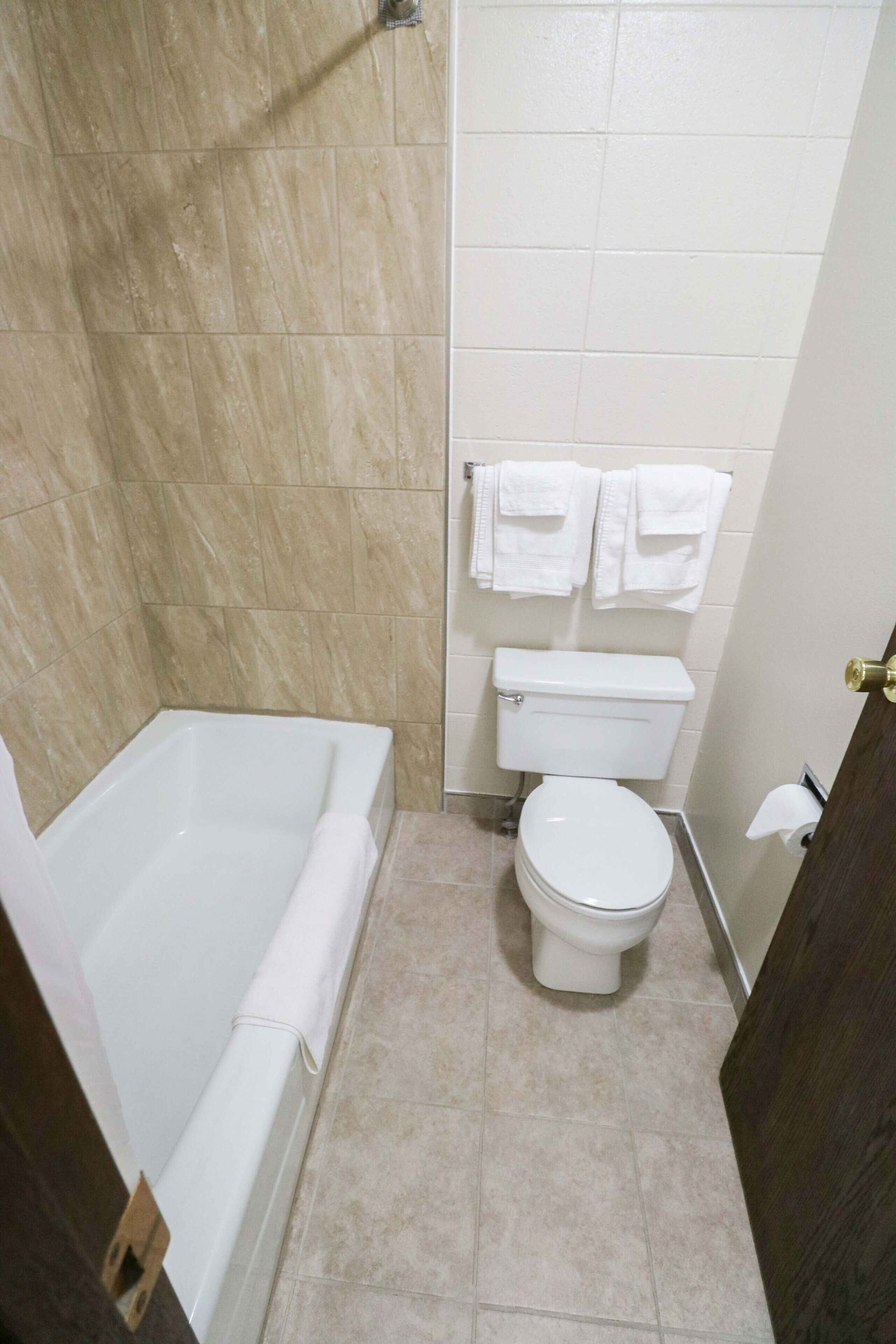 Een badkamer met een badkuip, toilet en handdoekhouder.
