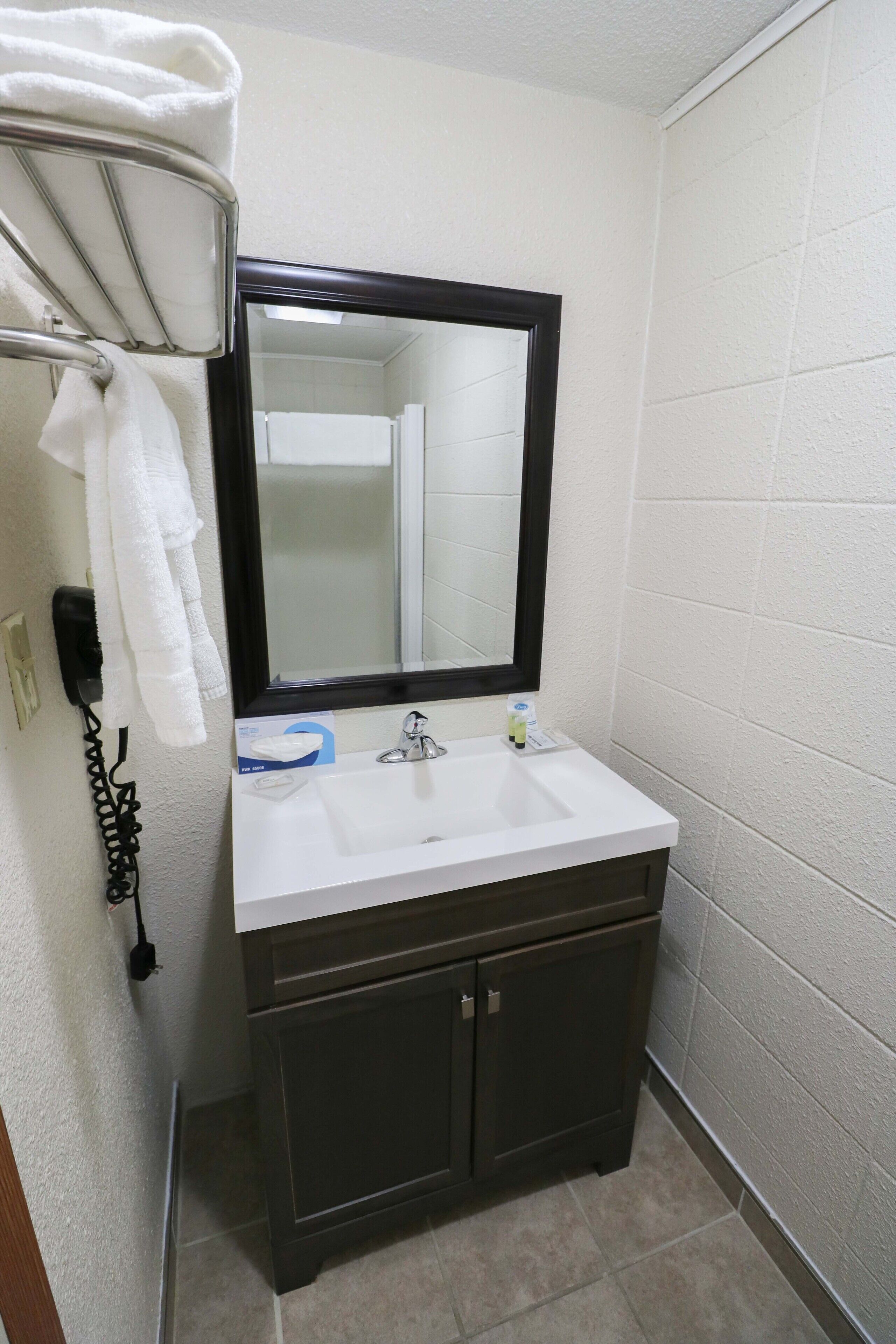 A bathroom with a white sink, dark cabinets, a mirror, and a towel rack.
