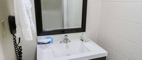 A bathroom with a white sink, dark cabinets, a mirror, and a towel rack.