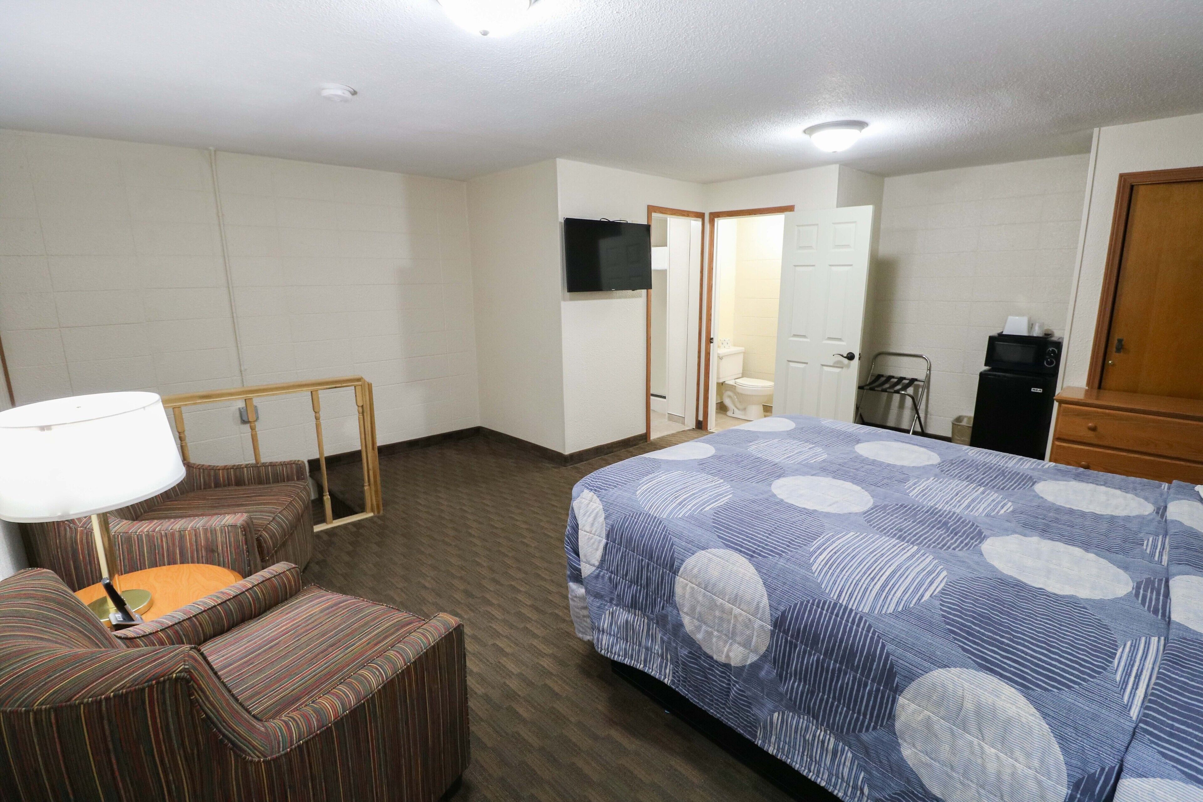 A hotel room with a bed, a TV, a desk, and a chair.
