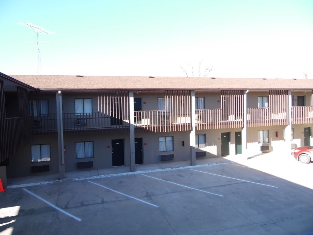 A multi-story motel with a parking lot in front.