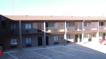 A multi-story motel with a parking lot in front.