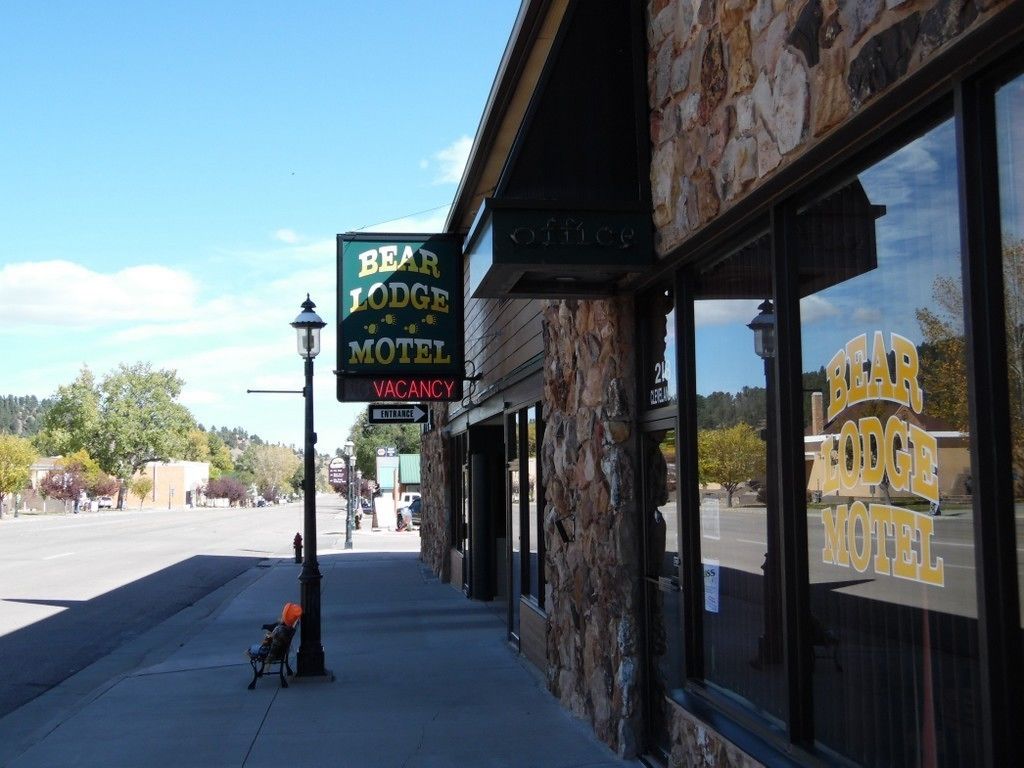 Motel Bear Lodge con un cartel de disponibilidad, fachada de piedra y vista despejada a la calle.