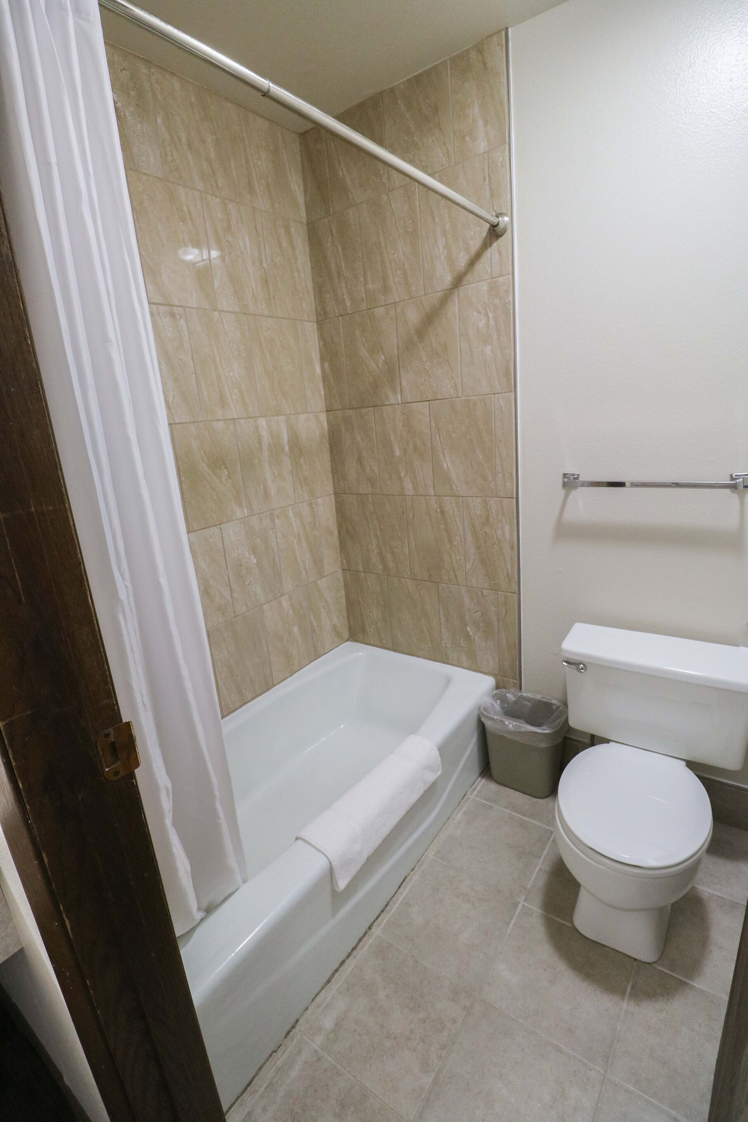 Un baño con bañera, inodoro y cortina de ducha.