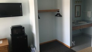 A hotel room with a flat-screen TV, a coffee maker, a wooden dresser, and a bathroom with a sink and mirror. - Day's End Motel (Wisconsin Dells)