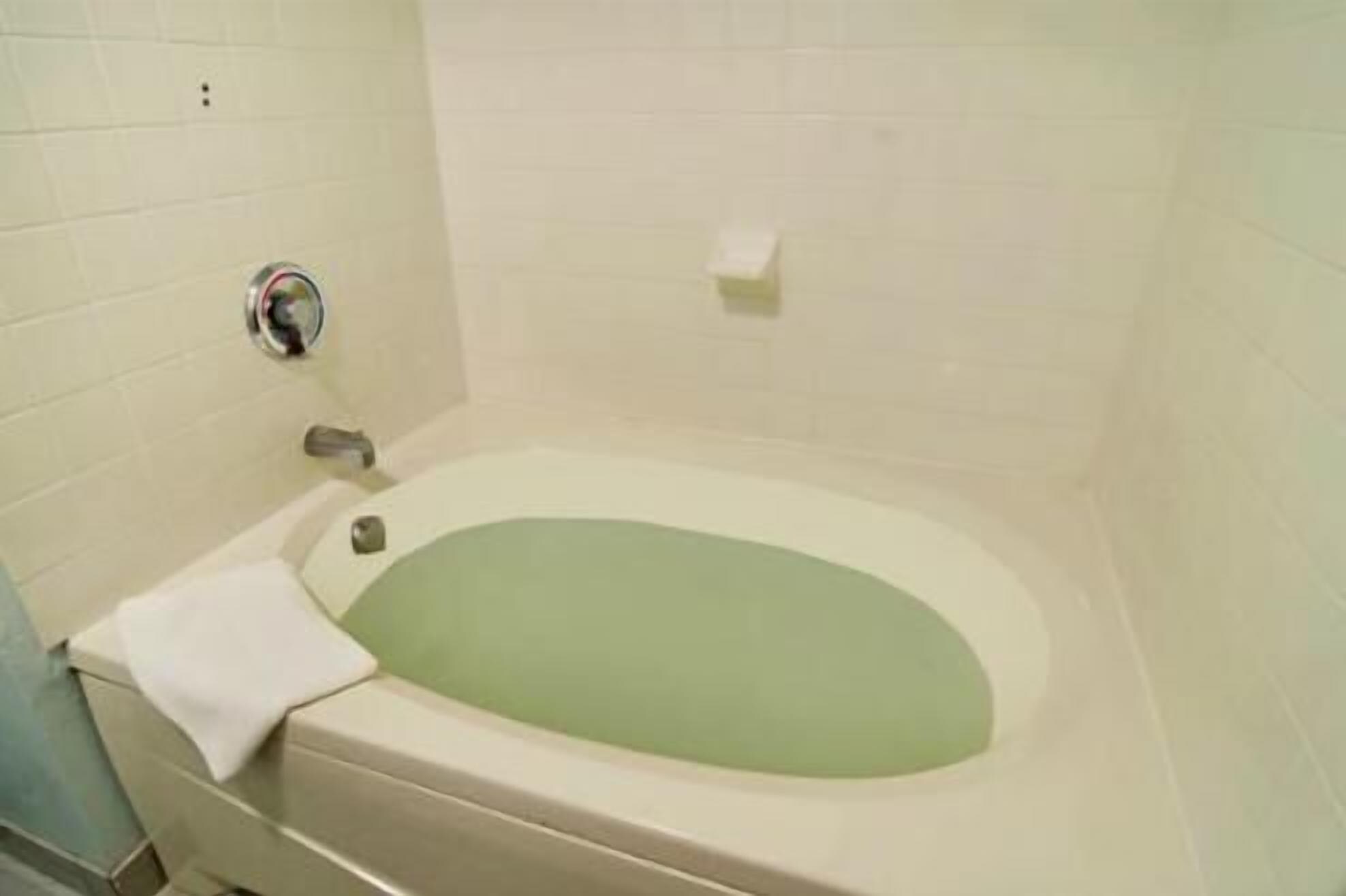A bathroom with a bathtub, a towel, and a toilet.
