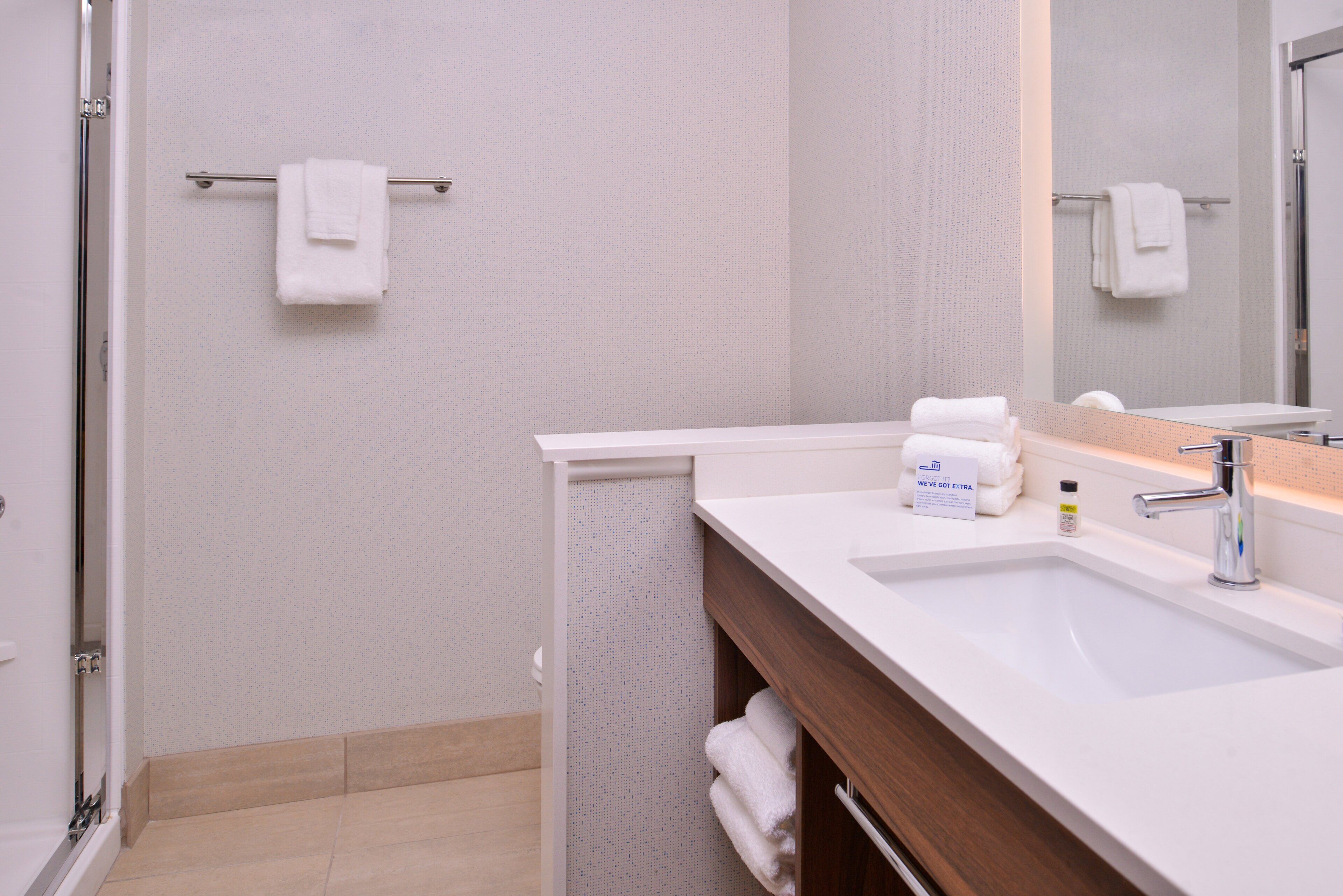 A modern bathroom with a white sink, a mirror, and a towel rack.