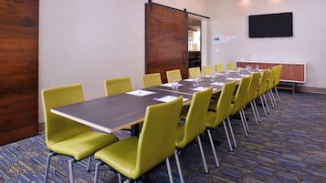 A conference room with a long table, yellow chairs, and a projector screen.