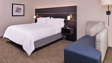 Una habitación de hotel con cama, mesita de noche, lámpara y una silla.