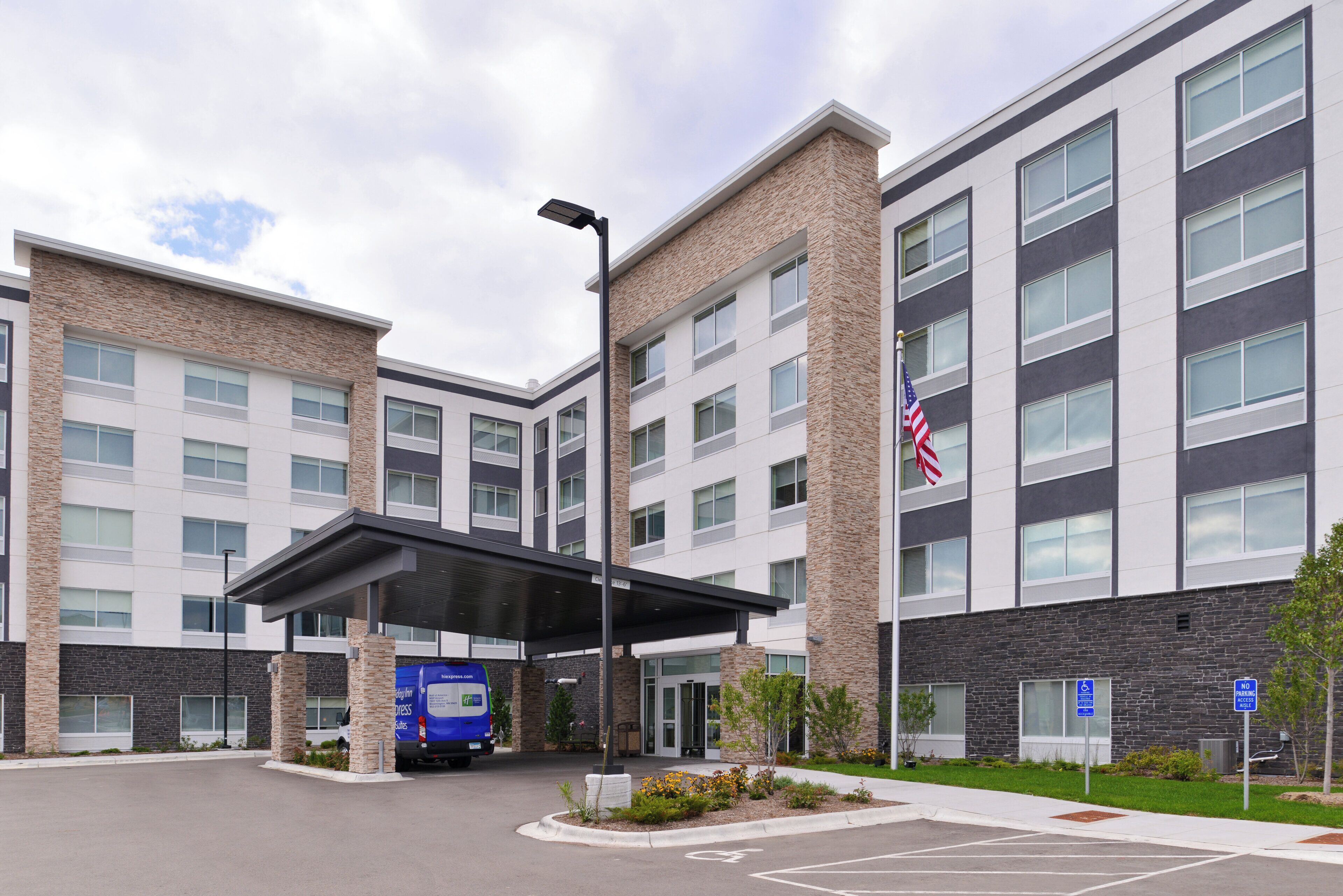A multi-story hotel with a covered entrance and a flagpole with an American flag.