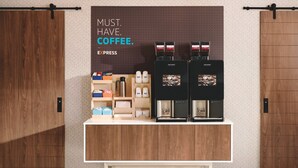 Een koffiehoek met twee koffieapparaten en diverse koffiekapsules en bekers.