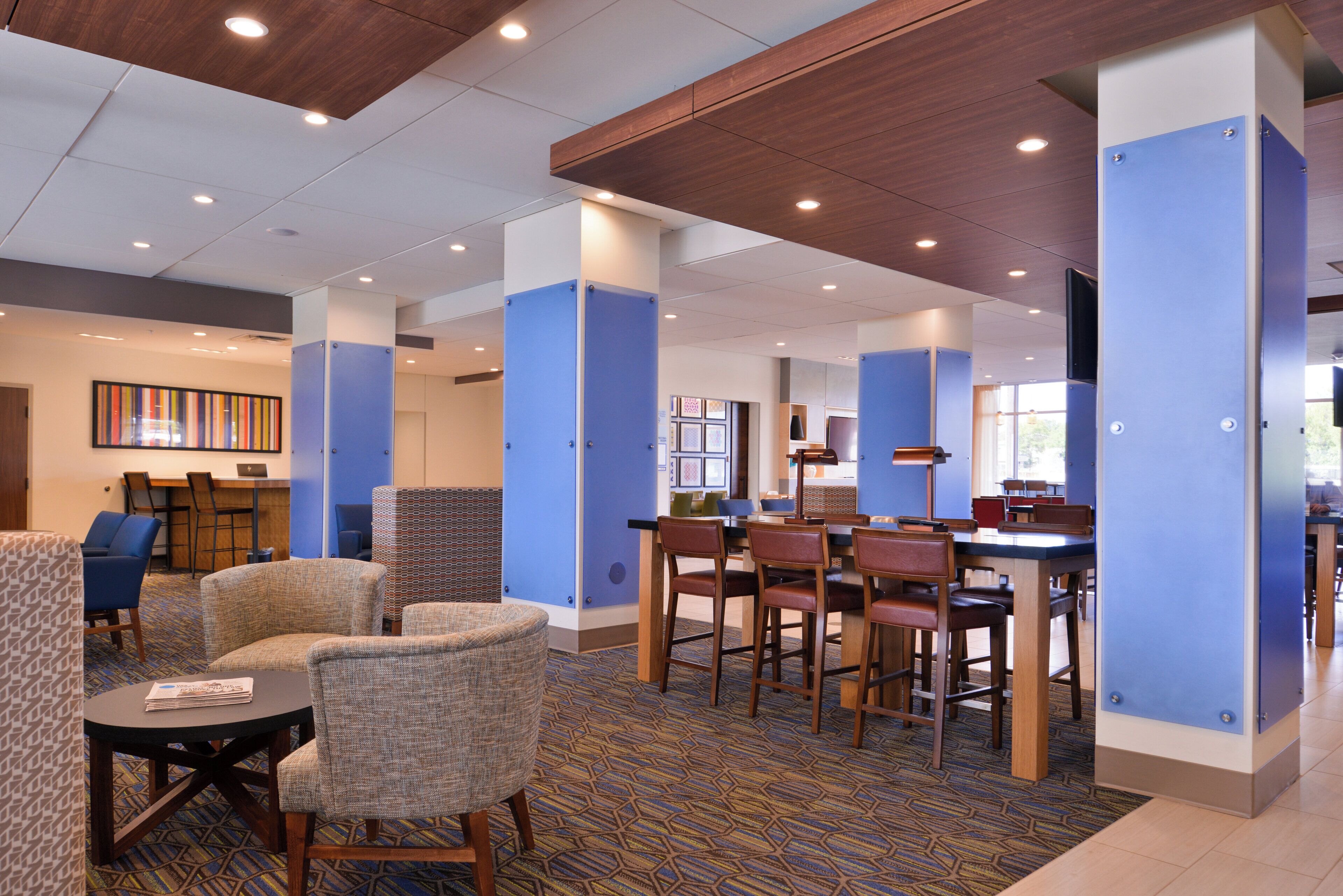 A hotel lobby with seating areas, a reception desk, and a patterned carpet.