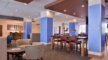A hotel lobby with seating areas, a reception desk, and a patterned carpet.