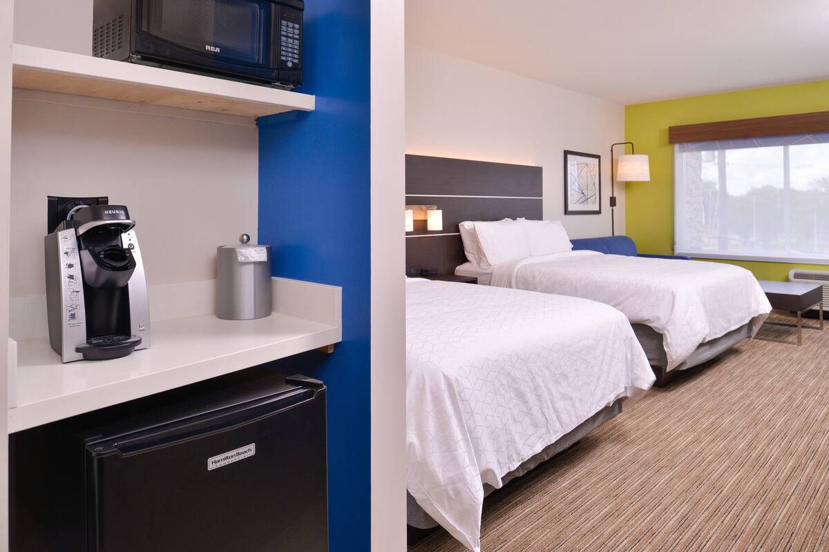 Een hotelkamer met een kitchenette, een bed, een nachtkastje en een raam met uitzicht.