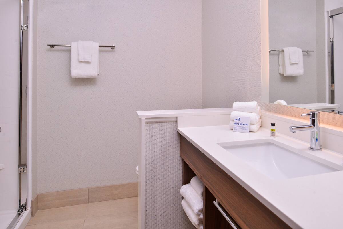 Een moderne badkamer met een witte wastafel, een spiegel en een handdoekhouder.