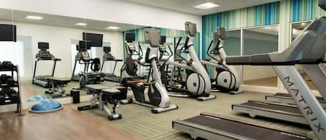 A gym with treadmills, elliptical machines, and weight equipment.
