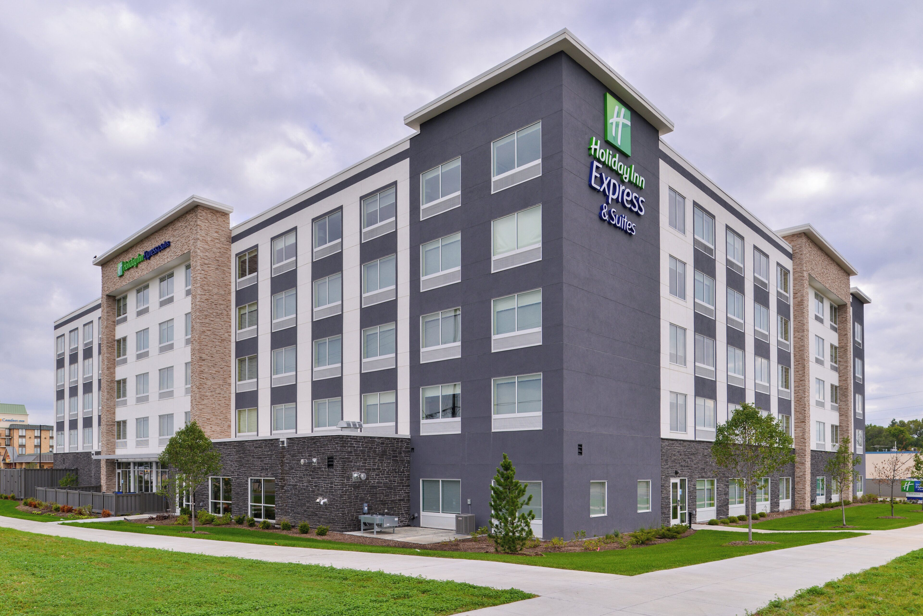 Un hôtel à plusieurs étages, doté d’une architecture moderne et d’une enseigne bien visible indiquant « Holiday Inn Express & Suites ».