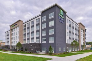 Un hôtel à plusieurs étages, doté d’une architecture moderne et d’une enseigne bien visible indiquant « Holiday Inn Express & Suites ».