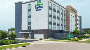 Een Holiday Inn Express & Suites gebouw met een modern ontwerp, met een ruime parkeerplaats en aangelegde groenvoorzieningen.