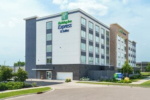 A Holiday Inn Express & Suites building with a modern design, featuring a large parking lot and landscaped areas.