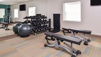 A gym with exercise equipment, a mirrored wall, and a window.