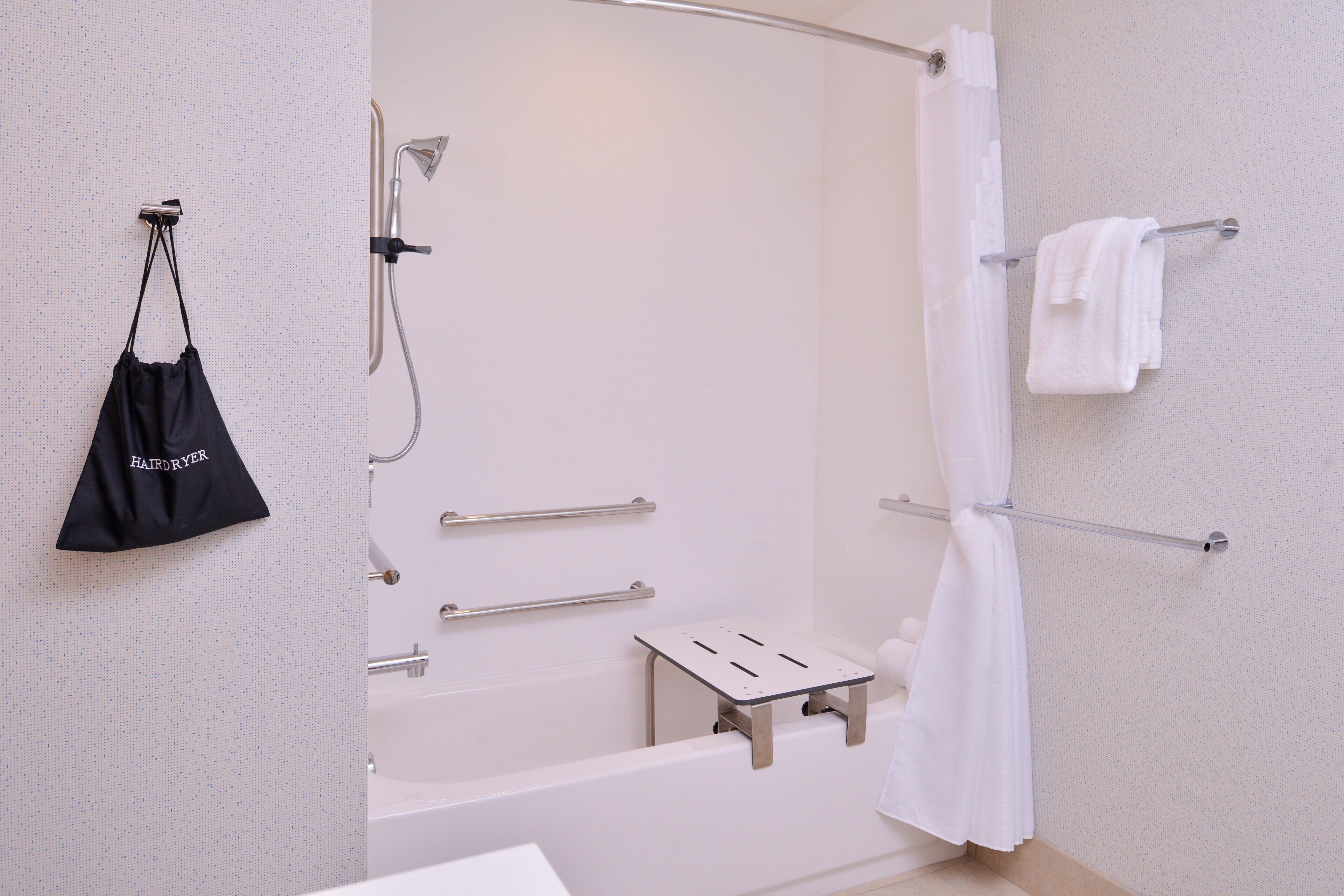 Casa de banho moderna com chuveiro, porta-toalhas e saco para secador de cabelo.