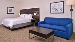 Een hotelkamer met een bed, een blauwe bank, een kleine tafel en twee wandlampen.