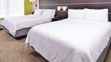 A hotel room with two beds, a nightstand, a lamp, and a window.