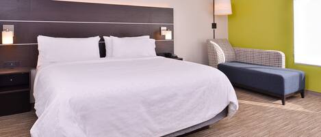 Una habitación de hotel con una cama grande, una mesita de noche, una lámpara y una silla.