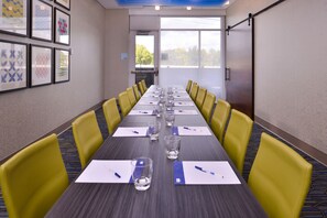 A conference room with a long table, yellow chairs, and framed artwork on the walls.
