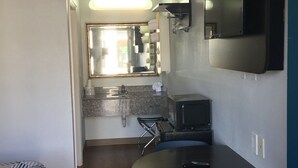 A compact kitchen with a dining area, a flat-screen TV mounted on the wall, and a small seating area with a table and chairs. - Motel 6 El Paso, TX - West (El Paso)