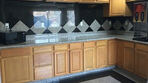 A kitchen with wooden cabinets, a black backsplash, and a coffee machine. - Motel 6 El Paso, TX - West (El Paso)