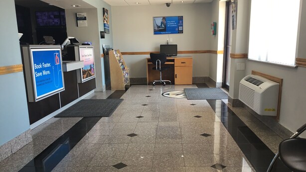 A hotel reception area with a check-in counter, a computer, and a seating area. - Motel 6 El Paso, TX - West (El Paso)