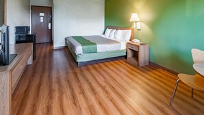 A hotel room with a bed, bedside table, lamp, and a desk with a computer and printer. - Motel 6 Drums, PA (Drums)