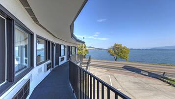 A balcony with a view of a body of water and a tree.
