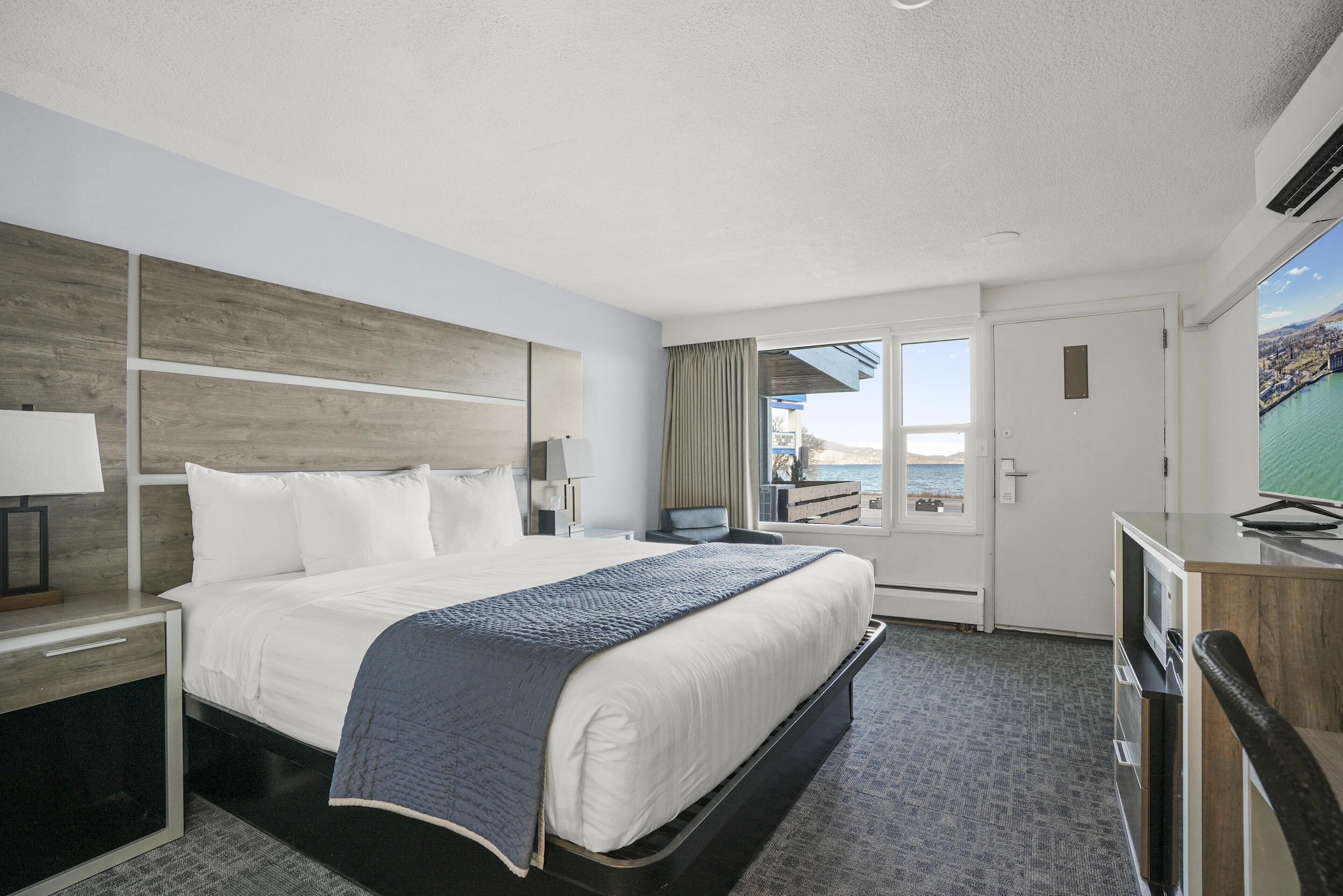 Een hotelkamer met een groot bed, een bureau met een computer, een televisie en uitzicht op zee.