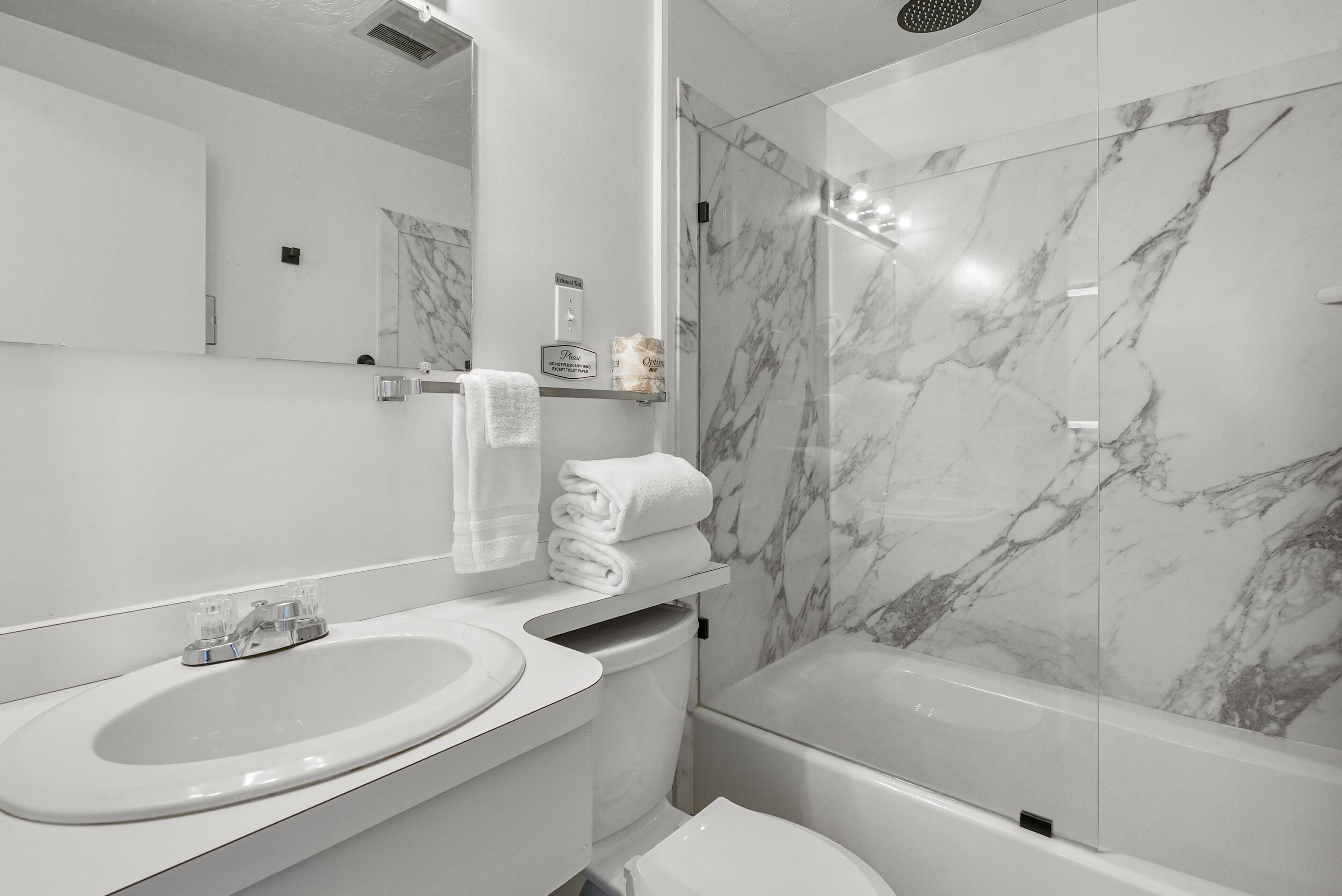 Une salle de bain moderne avec une douche en marbre, un lavabo et des toilettes.