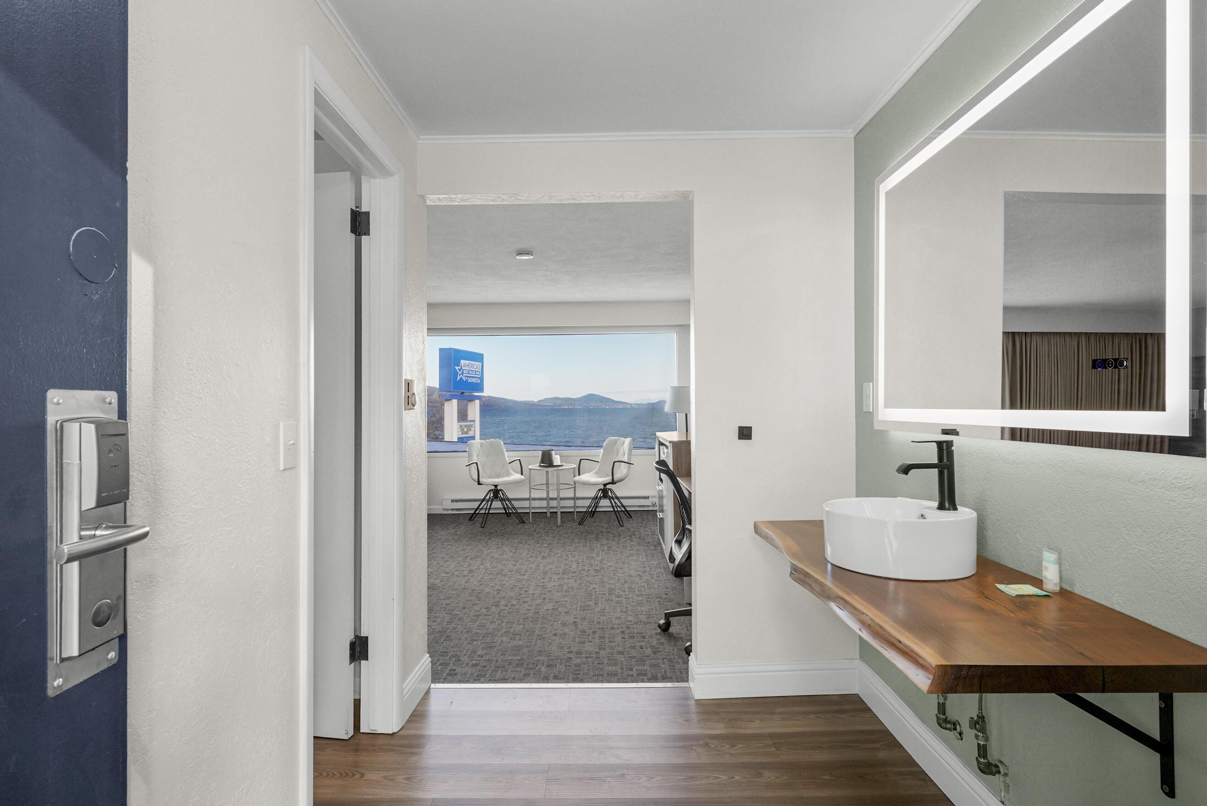 A hotel room with a wooden vanity, a large mirror, and a view of the mountains through the window.