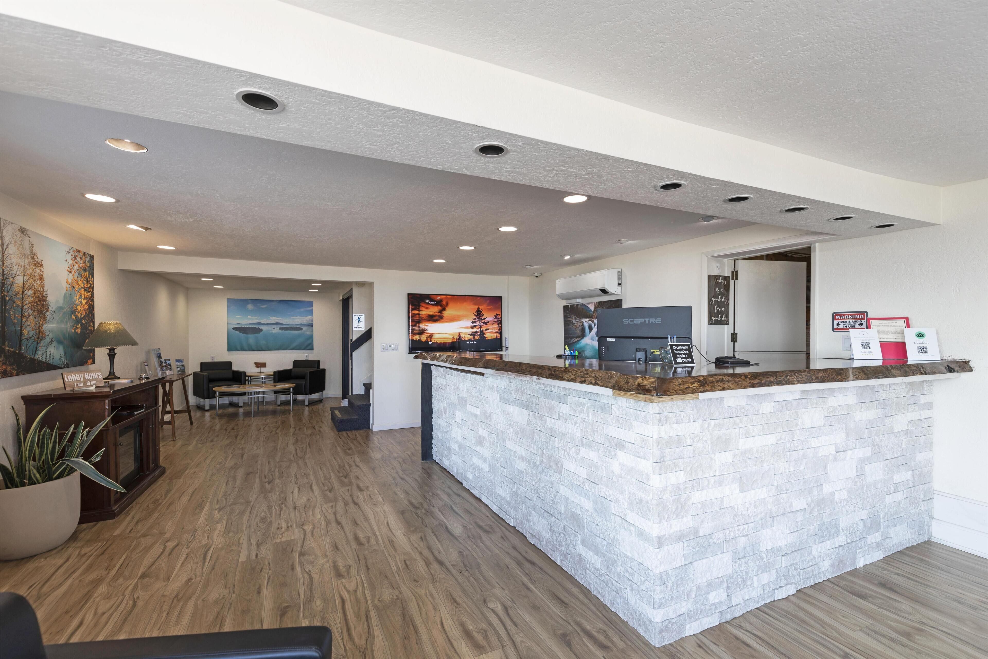 A reception area with a stone counter, wooden flooring, and a painting of a sunset.