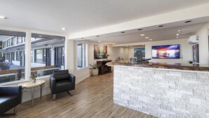 Una cocina moderna con una isla de mármol, un televisor grande y una zona de estar con mesa y sillas.