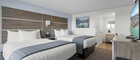 A modern hotel room with two beds, a desk, and a large window.