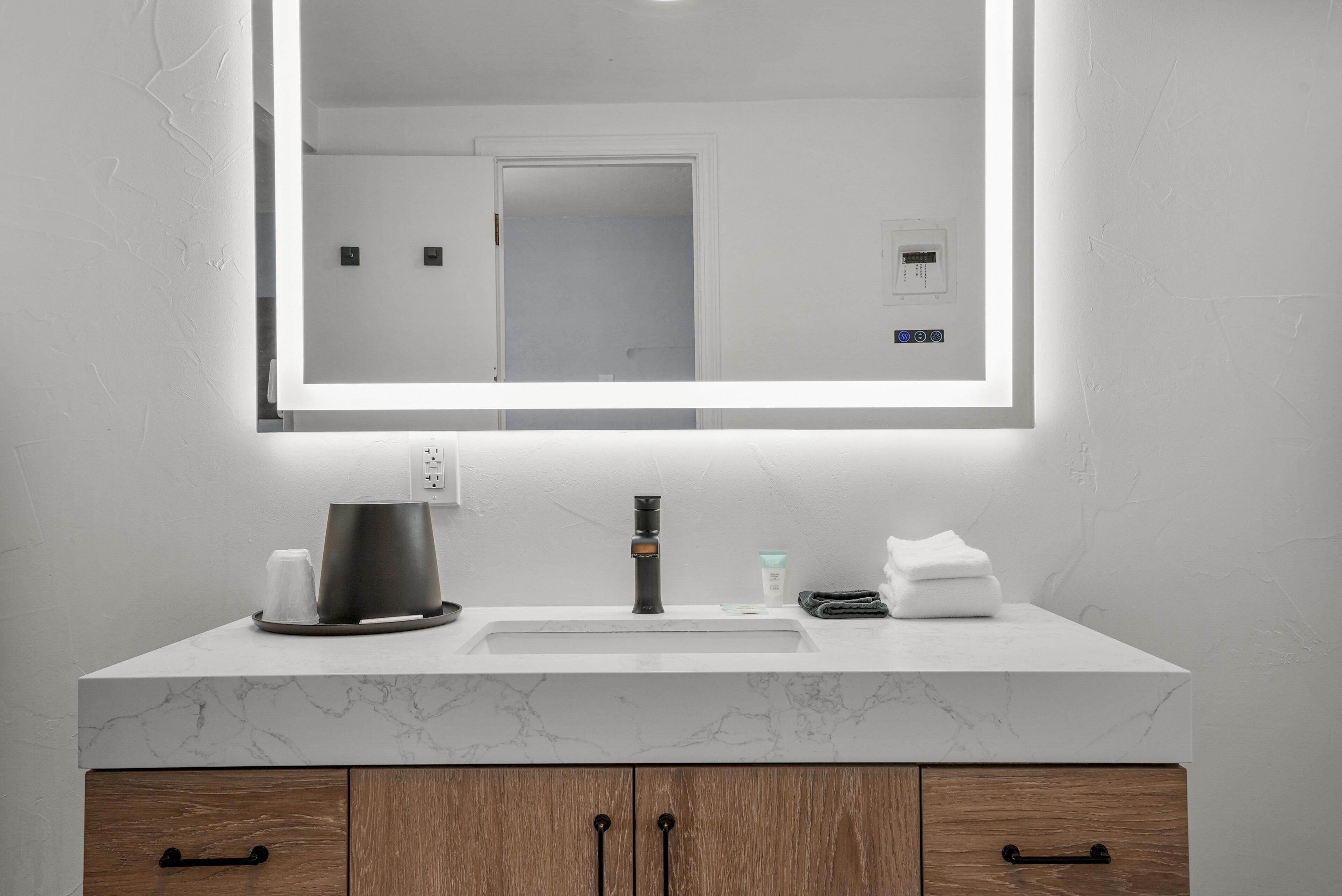 A bathroom with a marble sink, a coffee maker, and a mirror.