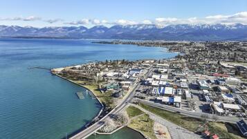 An aerial view of a coastal town with a marina, a bridge, and a mountain range in the background.