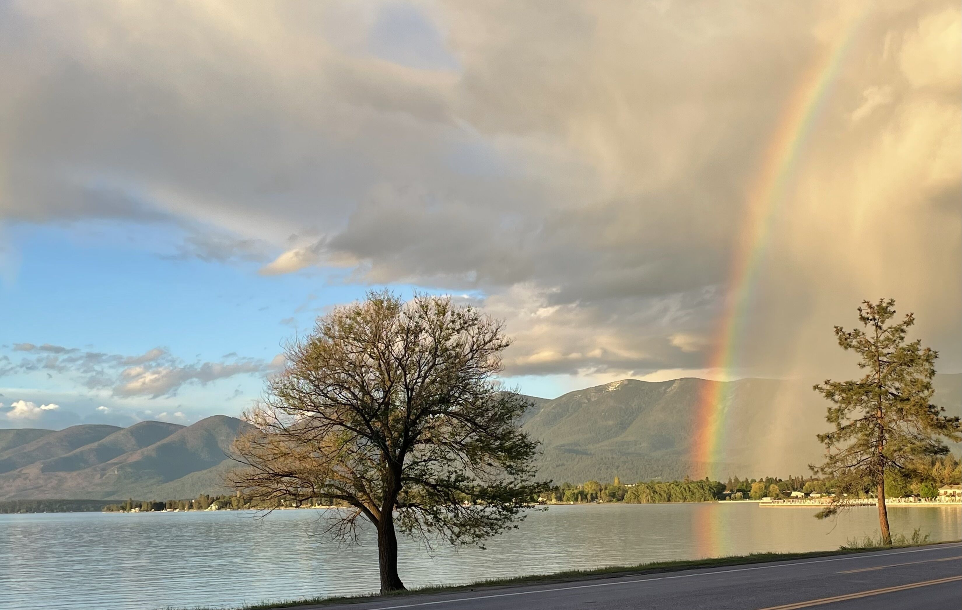 A lake with mountains in the background and a rainbow.