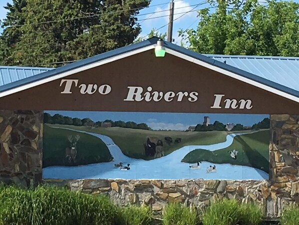 A sign for Two Rivers Inn with a mural of a river and ducks.