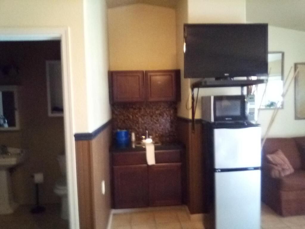A compact kitchen with a microwave, refrigerator, and wooden cabinets.