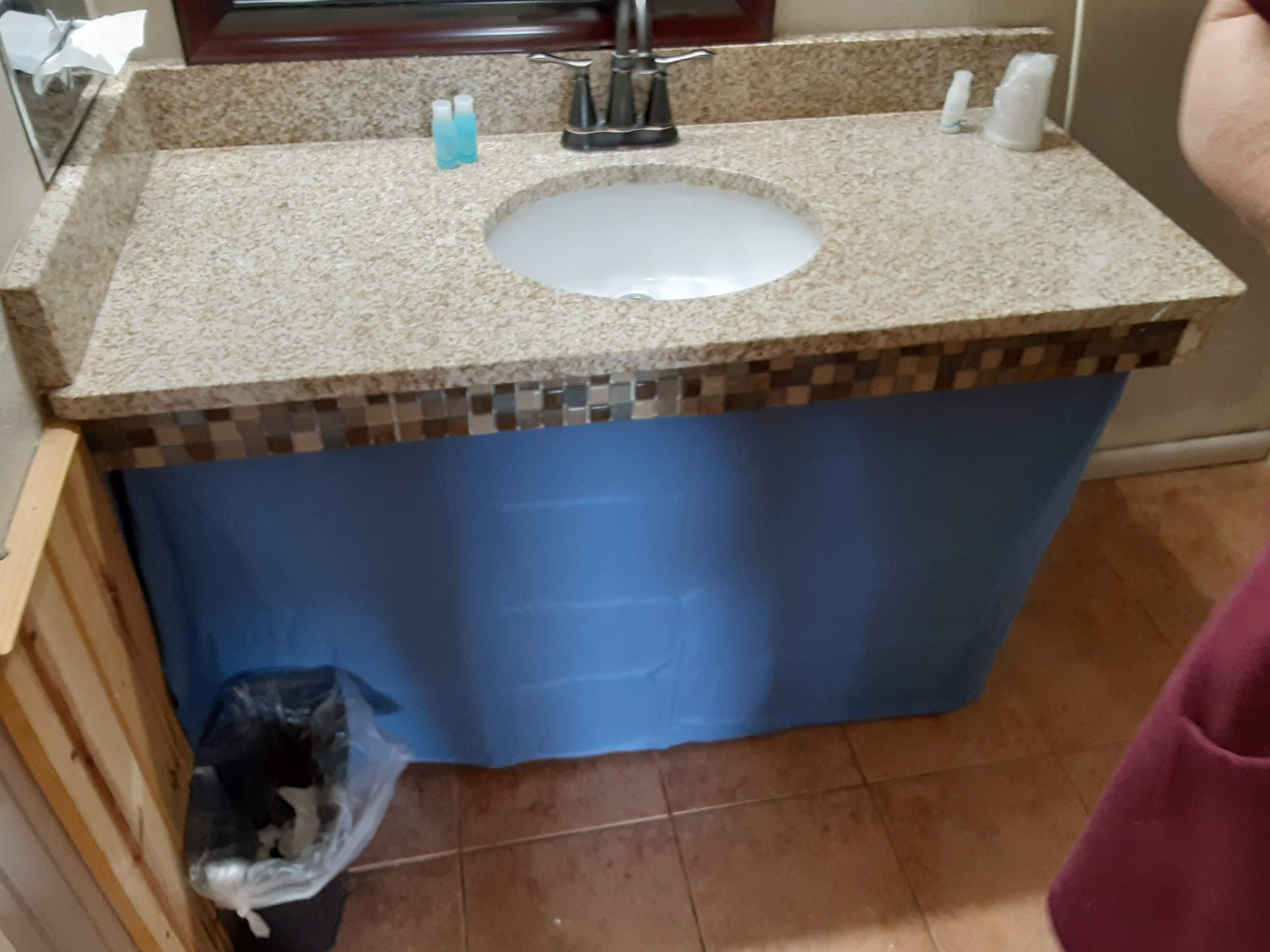 A bathroom with a granite countertop, a sink, and a blue shower curtain.