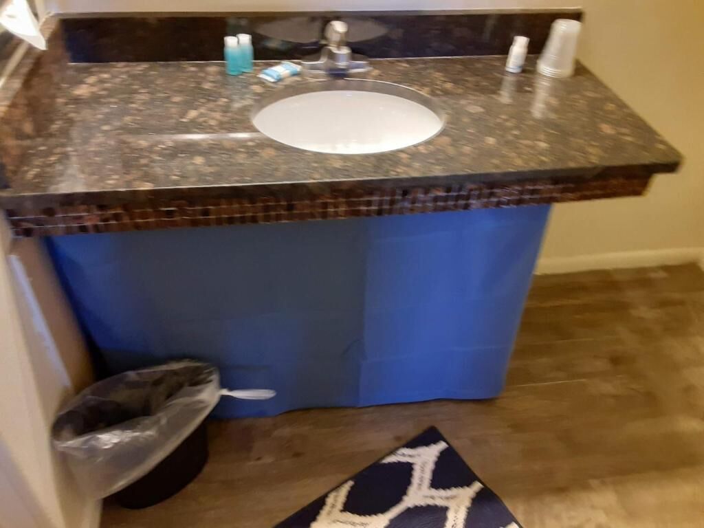 A bathroom with a granite countertop, a sink, and a blue shower curtain.