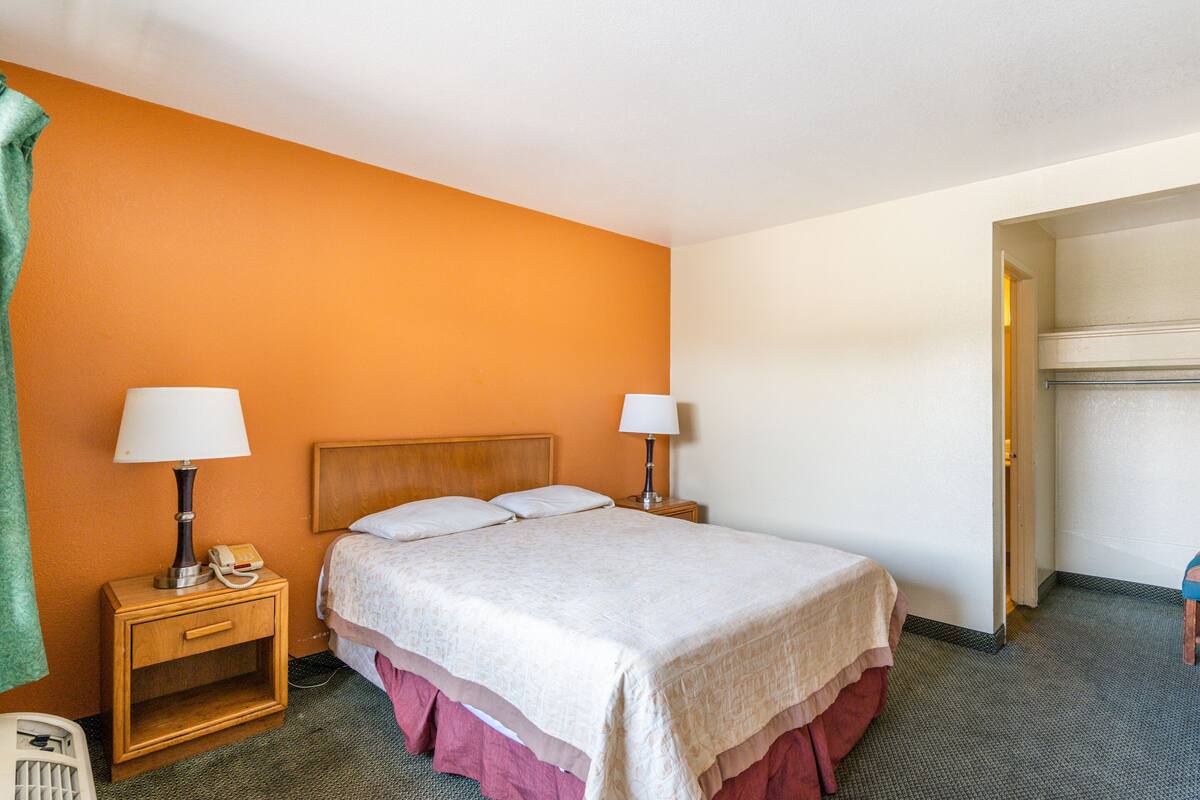 A hotel room with a bed, two bedside tables with lamps, a telephone, and a green towel.