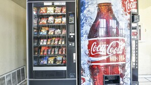 A vending machine with a Coca-Cola advertisement and a selection of snacks. - OYO Hotel Shreveport Airport North (Shreveport)